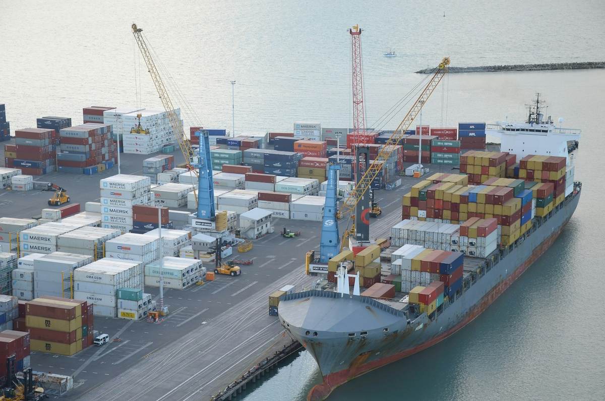 Aerial view of a container ship docked at a port terminal alongside stacked shipping containers