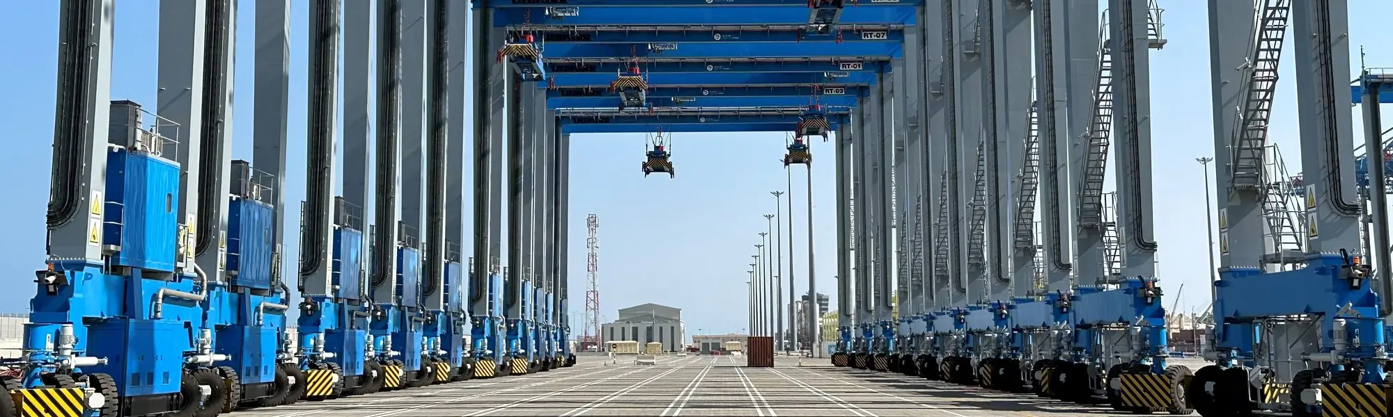 A row of automated straddle carriers and gantry cranes at a container terminal